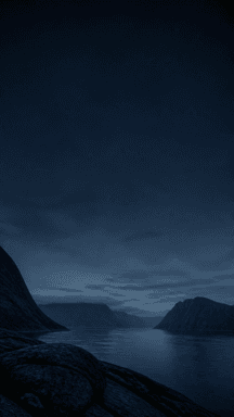 A still fjord between dark mountains beneath a broad blue night sky.