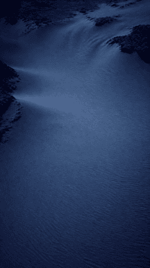 Soft ridges and shadows curve across blue moonlit sand dunes.